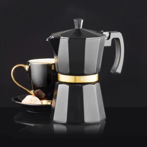 Czarna kawiarka ciśnieniowa ze złotym paskiem. Za nią elegancka czarno-złota filiżanka do espresso.