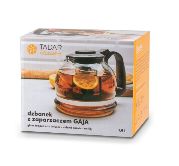 Kolorowe opakowanie (pudełko) produktu prezentujące szklany dzbanek z zaparzaczem w ciepłej aranżacji kuchennej. Na pudełku widoczna jest grafika przedstawiająca gotowy dzbanek wypełniony napojem, stojący na drewnianej powierzchni w otoczeniu owoców.