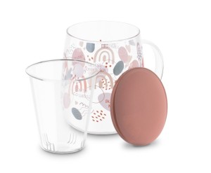 Szklany kubek z kolorową grafiką o który opiera się ceramiczna różowa pokrywka. Przed kubkiem wyciągnięty szklany zaparzacz.